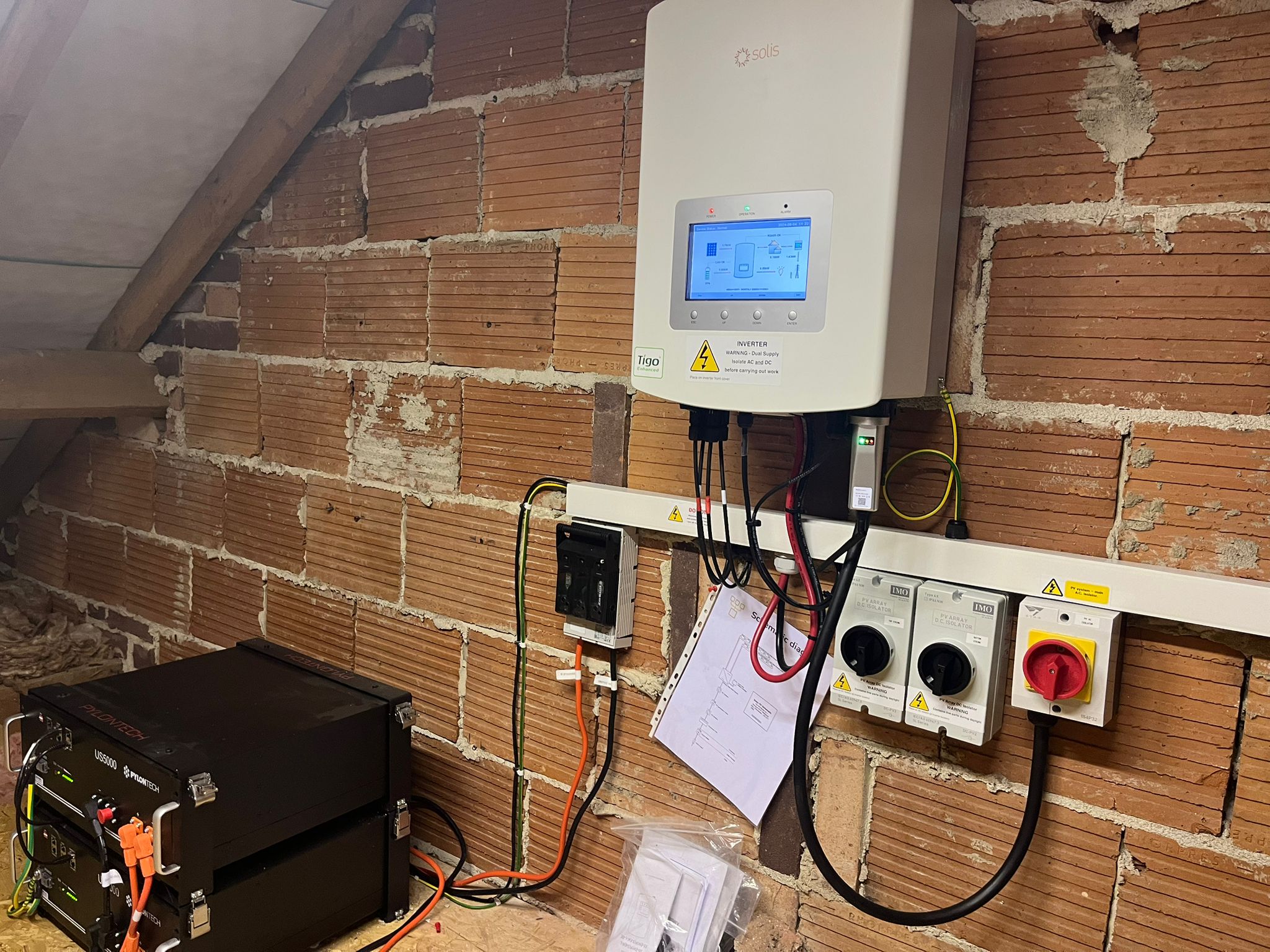 Solar power inverter setup in an attic with wooden beams and comprehensive wiring.